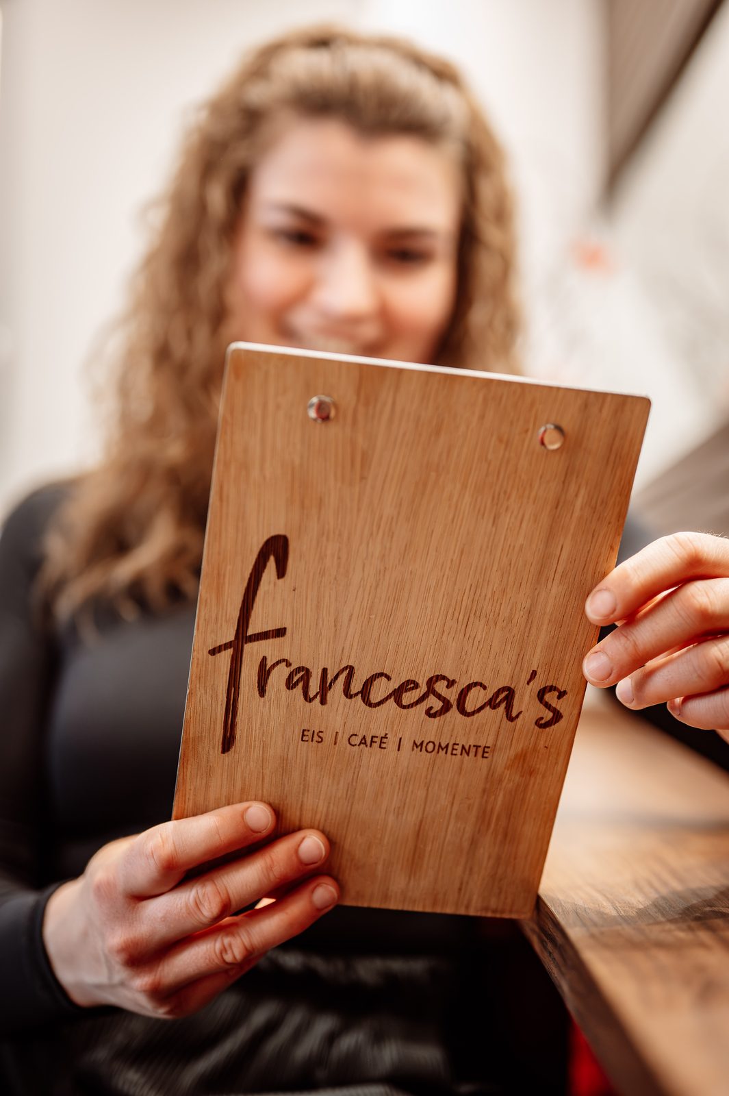 Franzi hält ein Holzbrett mit dem francesca's-Logo